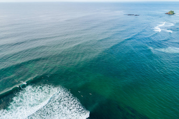 Vista superior do drone de muitos surfistas esperando para pegar a próxima onda durante o surf no oceano indiano
 - Foto, Imagem