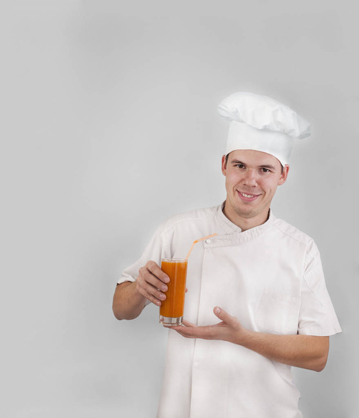 Handsome man wearing chef uniform drinking fresh orange juice. - Foto, Imagen