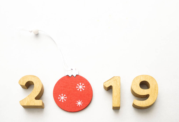 Number 2019, composed of wooden numbers, decorated with Christmas red ball. Christmas composition, 2019 happy new year. isolated on white background.   - Foto, immagini