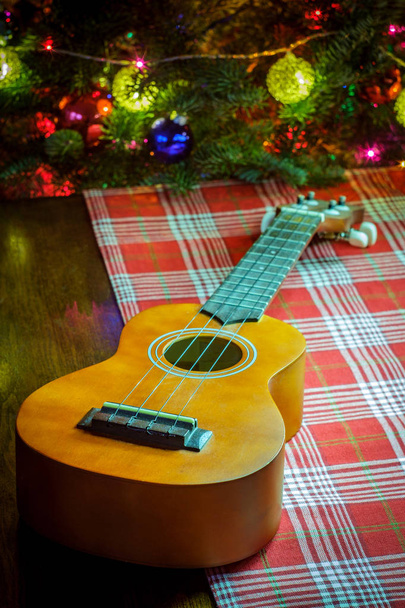 Seasonal holiday musical instrument ukulele with Christmas tree background - Photo, Image