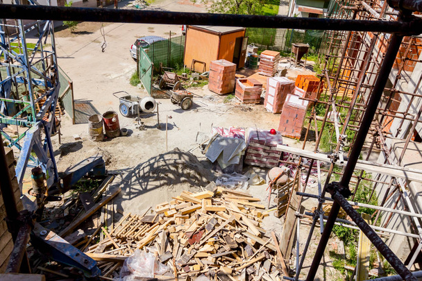 Boven uitzicht op bouwplaats, steiger, verpakt, opgestapeld middelen en houten vuilnis. - Foto, afbeelding
