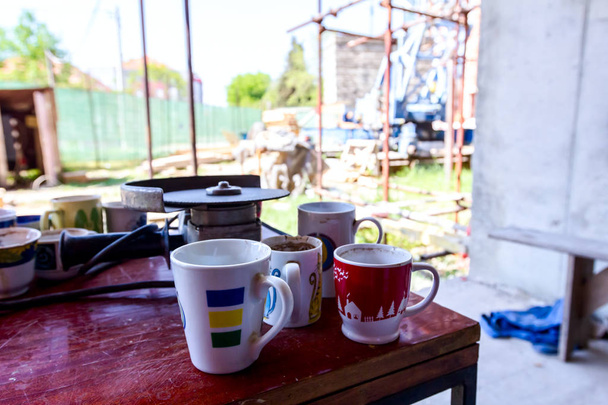 Pocas tazas de café vacías colocadas en la mesa después del descanso en el sitio de construcción
. - Foto, imagen