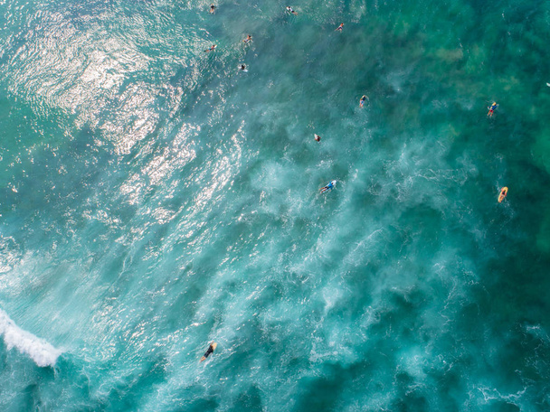 Aerial view from drone of surfers paddling for catching waves during surfing in the indian ocean - Фото, зображення