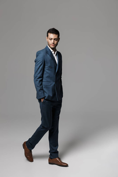 Full length image of businesslike arabic man 30s in formal suit walking isolated over gray background - Fotografie, Obrázek
