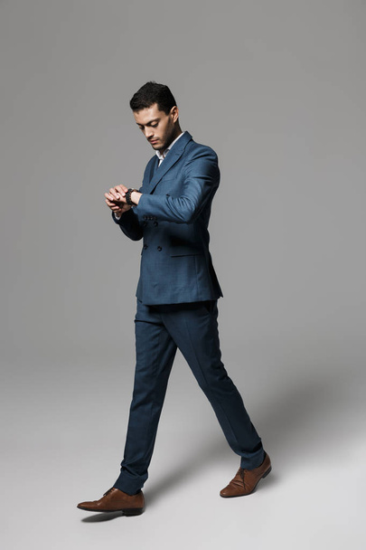 Full length image of businesslike arabic guy 30s in formal suit strolling isolated over gray background - Valokuva, kuva