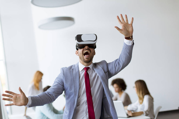 L'homme d'affaires faisant l'exercice de formation d'équipe pendant le séminaire de team building en utilisant des lunettes VR au bureau
 - Photo, image
