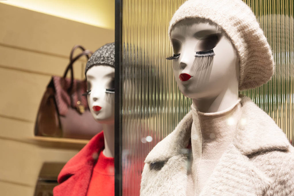 Schaufensterpuppen im Geschäft mit leuchtenden Lippen und langen Wimpern demonstrieren Winterkleidung - Foto, Bild
