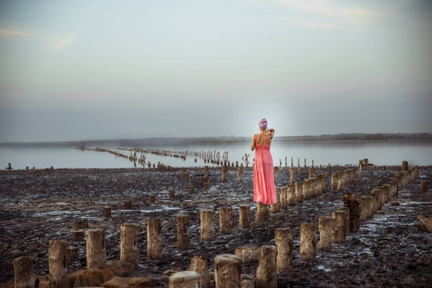 Красивая женщина в коралловом платье стоит на соляной колонне
. - Фото, изображение
