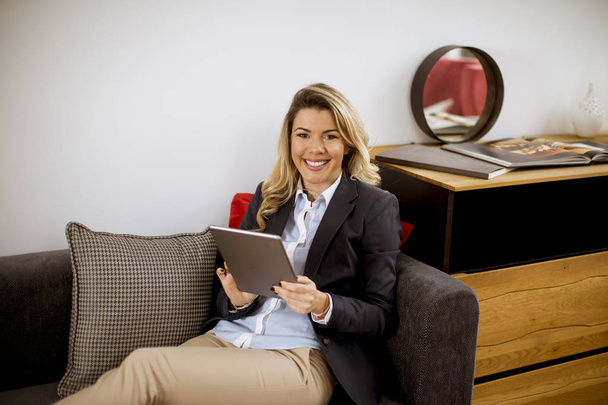 Giovane donna d'affari allegra a riposo con tablet sul divano moderno
 - Foto, immagini