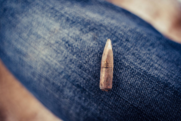 Bullet After Being Shot Put on the Blue Jeans Background with Ballistic Marks on it - Vintage Film Look - Photo, Image