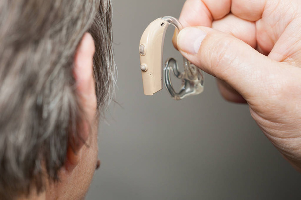 Closeup senior woman with hearing aid in her ear. Health care, hear amplify, device for the deaf. - Фото, зображення