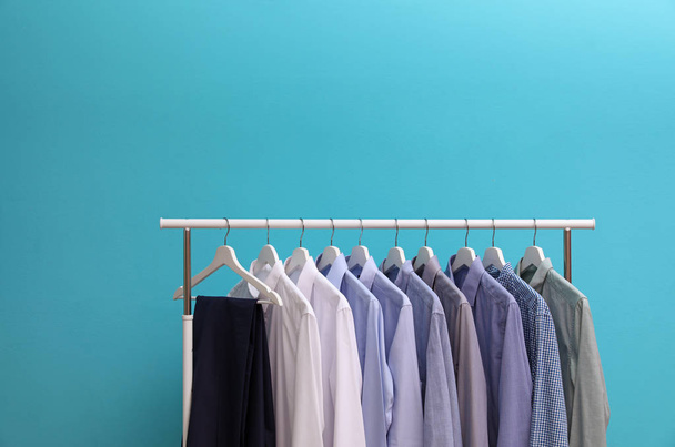 Wardrobe rack with men's clothes on color background. Space for text - Foto, imagen