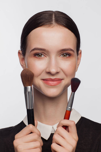Beautiful woman holds makeup brushes in her hands - Fotografie, Obrázek