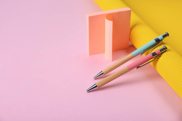 Composición con bolígrafos y notas adhesivas sobre fondo de color. Espacio para texto
 - Foto, Imagen