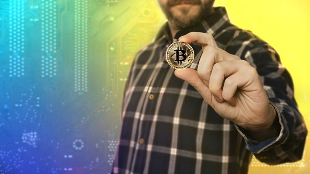 Kryptowährung Bitcoin. Mann hält Symbol der Kryptowährung in der Hand - elektronisches virtuelles Geld für Web-Banking und internationale Netzwerkzahlung, selektiver Fokus, getönt - Bild - Foto, Bild