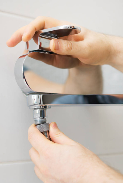 Plumber hands fixing shower mixer on modern water tap. - Photo, Image