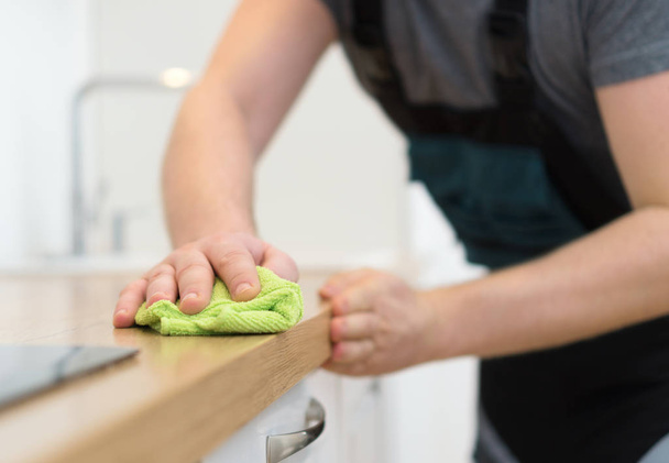 Úklidové služby koncept. Muž čištění kuchyňského nábytku. - Fotografie, Obrázek