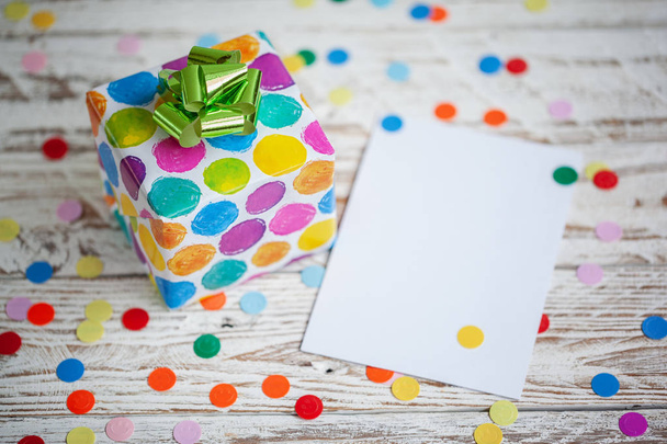 Colorful gift box with empty blank on wooden table. Holiday greeting card - Foto, imagen