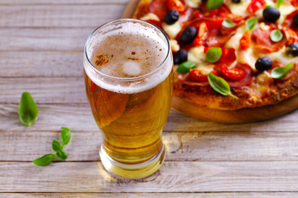 Glass of beer and pizza on wooden table. Beer and food concept. Ale. - Photo, image