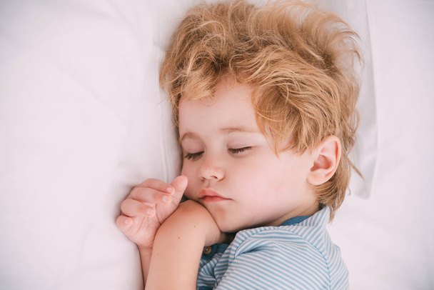 Sweet dreams, sleeping baby with white space pillow. Gentle photo in white tones with cute dreamy boy. Tender baby face, purity and innocence. Healthy child sleep, how to put baby to sleep - Photo, Image