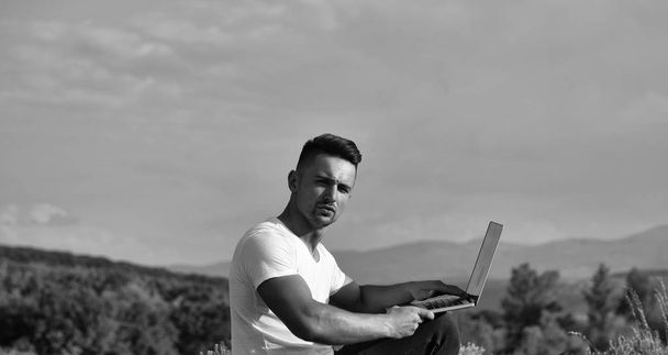 Pensive muscular man with laptop outdoor - Foto, Imagen