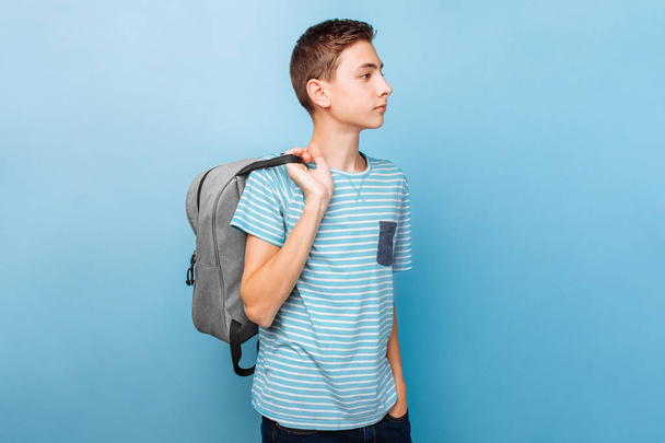 Cute teenager with a briefcase, student, on a blue background - Foto, imagen