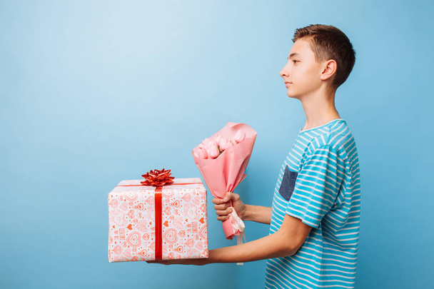 Teen boy gives a gift and flowers, a man in love - Φωτογραφία, εικόνα