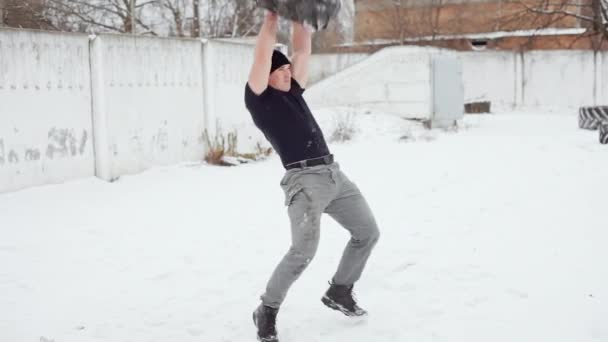 Muskularny mężczyzna zgłasza opony gumowe na siebie ćwiczeń crossfit w zimie - Materiał filmowy, wideo