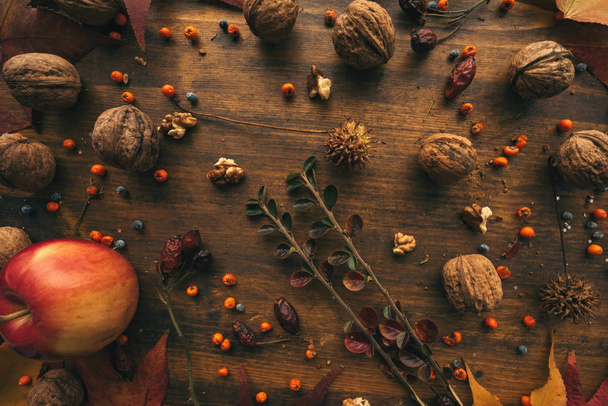 Rustic top view flat lay autumn arrangement decoration with some fruit and dry maple leaves on wooden table - Фото, зображення