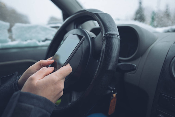 Textos dans la voiture garée pendant que la neige tombe à l'extérieur, gros plan des mains tapant le message sur le téléphone portable, mise au point sélective
 - Photo, image