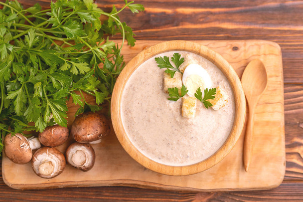 Tasty pureed mushroom soup in wooden bowl with ingredients. Healthy food concept. Rustic wooden background. Top view. Copy space - Foto, afbeelding
