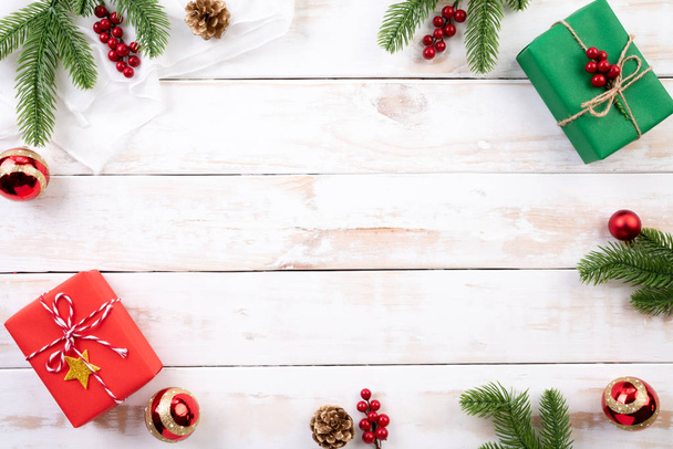 Vánoční pozadí konceptu. Pohled Vánoce, zelené a červené krabičky s smrkových větví, šišky, červené bobule shora a zvonek na bílém pozadí dřevěná. - Fotografie, Obrázek