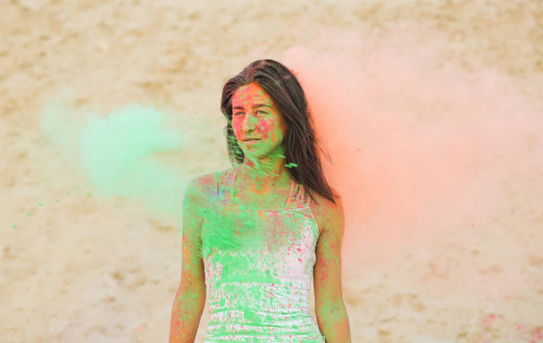 Bella donna bruna in posa con esplodere verde e arancione secco Holi polvere nel deserto
 - Foto, immagini