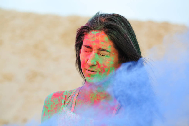 wunderschöne brünette Frau posiert in der Wüste mit explodierendem blauen, trockenen Holi-Puder - Foto, Bild