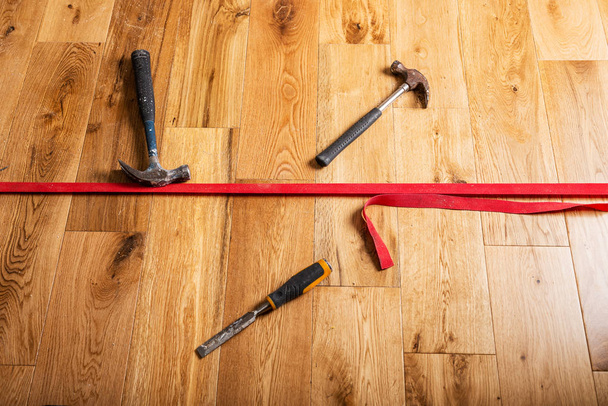 El proceso de renovación de la casa con el cambio del suelo de las alfombras a la madera de roble macizo. Diferentes herramientas y materiales en el nuevo piso
  - Foto, Imagen