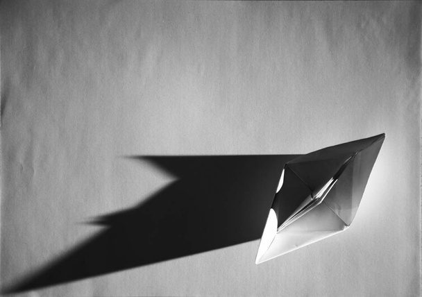 El barco de papel, origami, está haciendo sombras agudas a escala de grises. - Foto, imagen
