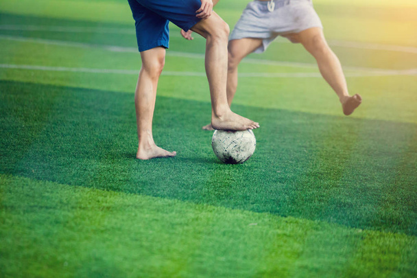 Les joueurs de football qui ne portent pas de chemise de sport et les pieds nus piégent et contrôlent le ballon pour tirer au but. Les joueurs de football se battent en frappant le ballon
. - Photo, image