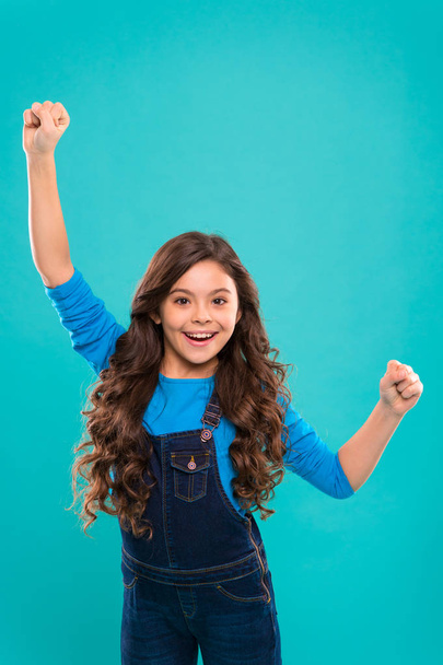 Girl cute child long curly hair happy smiling. Child psychology and development. Happy winner. Celebrate victory or achievement. Successful happy kid. Achieve success. Kid cheerful celebrate victory - Φωτογραφία, εικόνα