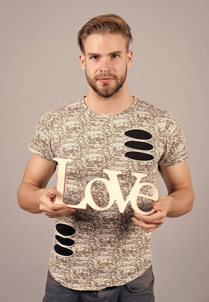 Man with serious face hold wooden love word, design - Valokuva, kuva