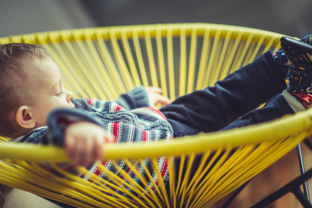Söpö vauva makaa rauhallisesti keltaisessa tuolissaan
 - Valokuva, kuva
