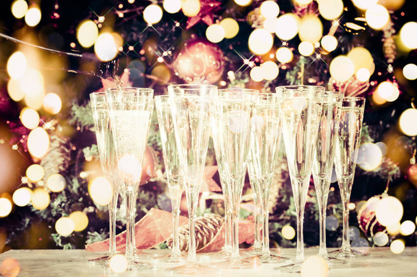 Gläser zum Feiern auffüllen. viele Gläser Champagner mit Weihnachtsbaum Hintergrund. Parteiaufbau. Hintergrund der Feiertage. traditionelle rote und grüne Weihnachtsdekoration mit Lichtern. Ferienparty. waagerecht, funkelnd und gestrafft. Festtagsstimmung - Foto, Bild