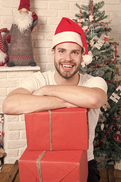 Man in santa hat smile with boxes at christmas tree - Photo, Image
