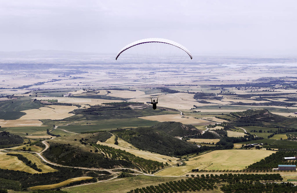 Paraglider silhouet vliegen over vallei in Loarre, Huesca, Spanje. - Foto, afbeelding