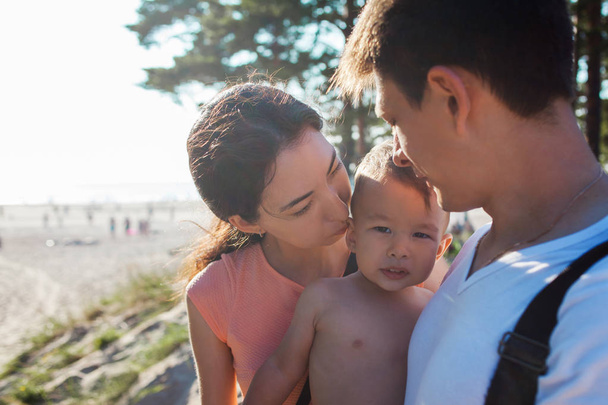 Portrait of happy young family with charming baby. Picnic on the beach - Photo, image