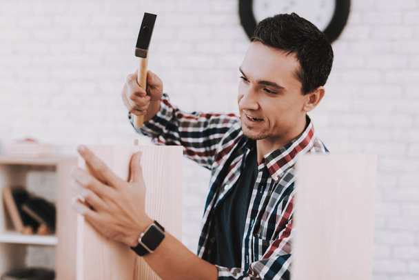 Young Man Assembling Wooden Bookshelf at Home. Wooden Bookcase. Selfmade Furniture. Man and Hobby. White Room. Engineer with Tool. Young Man at Home. Homemade Decoration. Modern Furniture. - Foto, immagini
