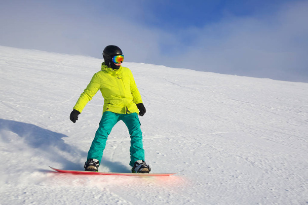 Snowboarder riding on slope at ski resort at sunny day - Foto, imagen