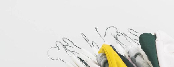 Pile of stylish clothes in pastel colors on white hangers over white background  - 写真・画像