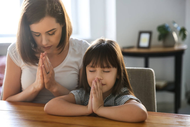 Madre con hija rezando en casa
 - Foto, imagen