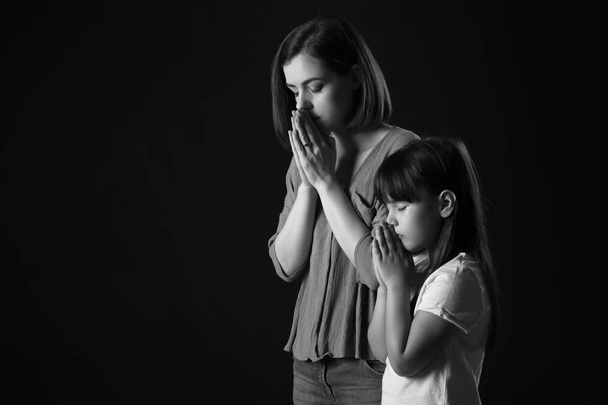 Praying mother and daughter on dark background - Photo, Image