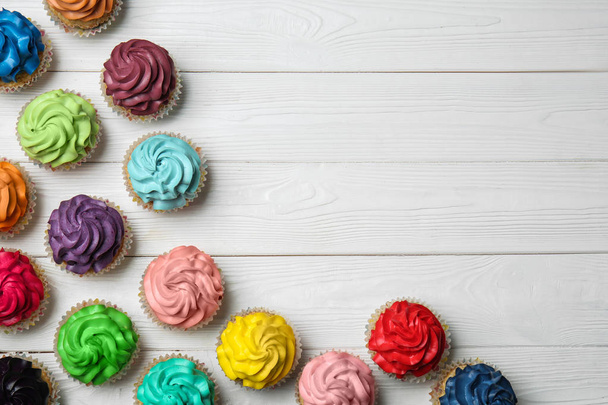 Coloridos cupcakes sobre fondo blanco de madera
 - Foto, Imagen